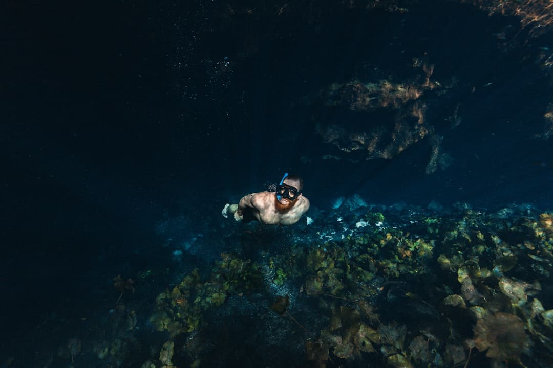 Brodaty mężczyzna w masce do snorkelingu eksploruje podwodną jaskinię.