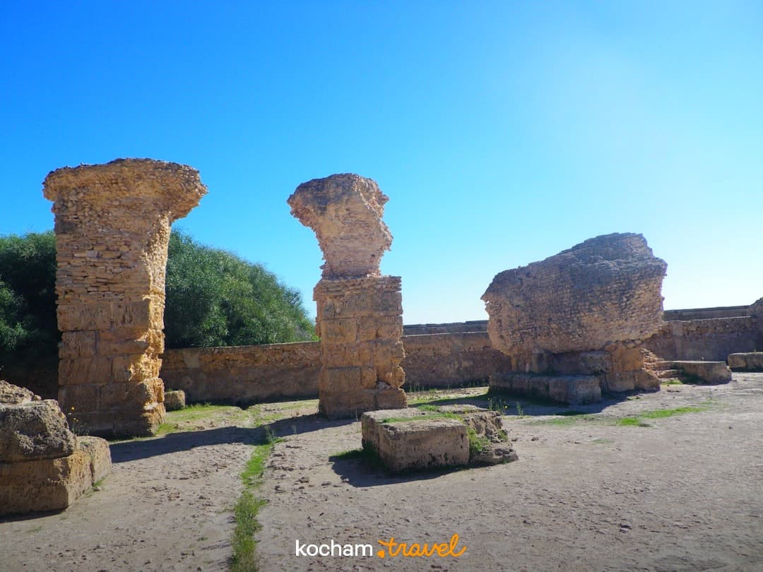 Starożytne ruiny kamiennych kolumn, stanowisko archeologiczne, błękitne niebo.