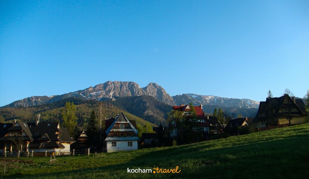 Giewont i tradycyjne domy w dolinie Tatr, zielone wzgórza.