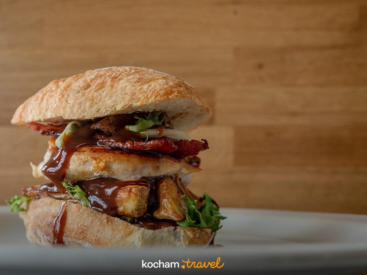 Pyszna kanapka z kurczakiem, bekonem i sosem BBQ na talerzu.