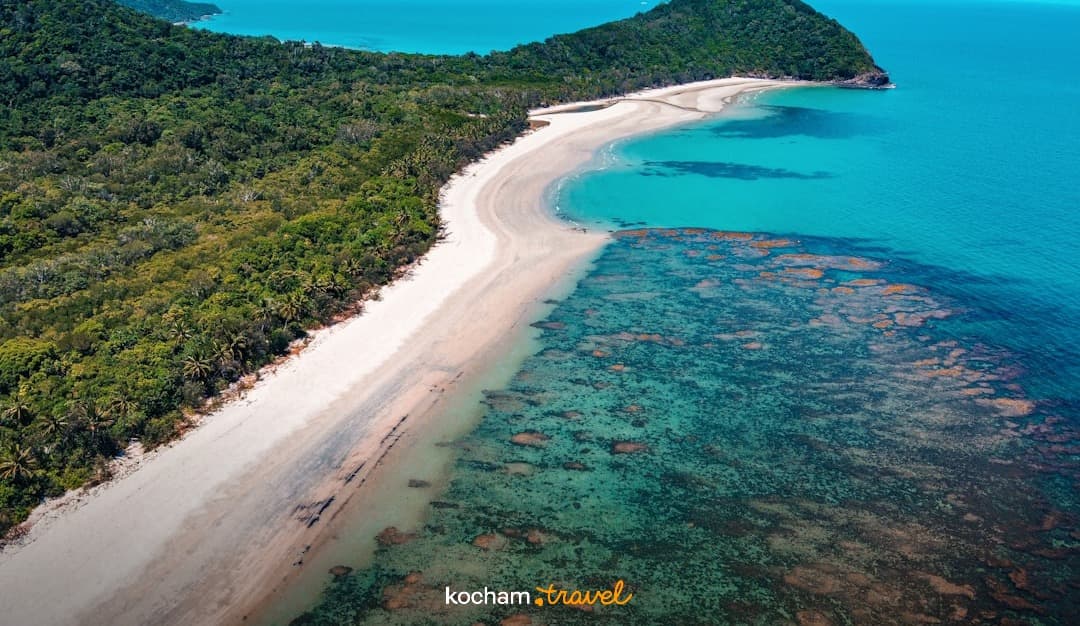 Egzotyczna plaża, turkusowa woda, rafa koralowa, bujny las, widok z lotu ptaka.