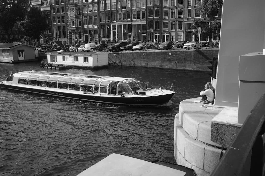 Łódź wycieczkowa "The Tulip" na kanale w Amsterdamie, historyczne budynki, osoba.