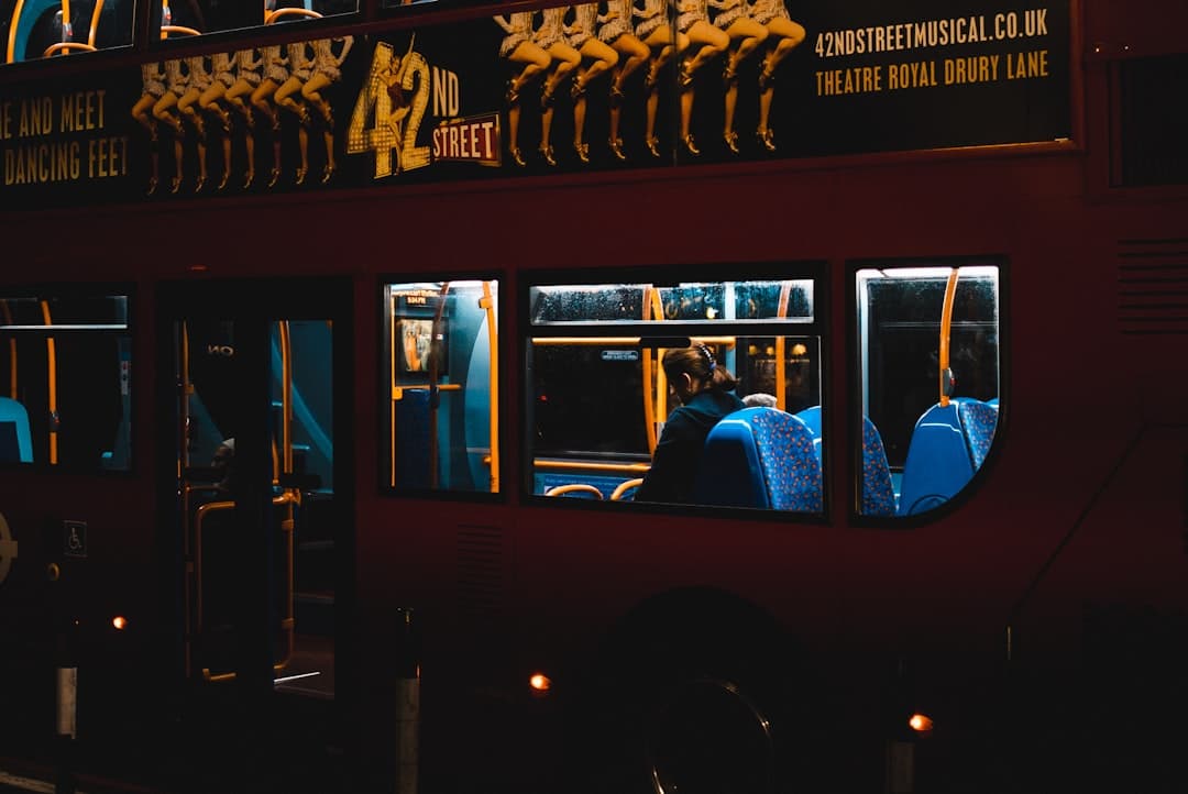 Osoba siedząca w nocnym autobusie piętrowym.