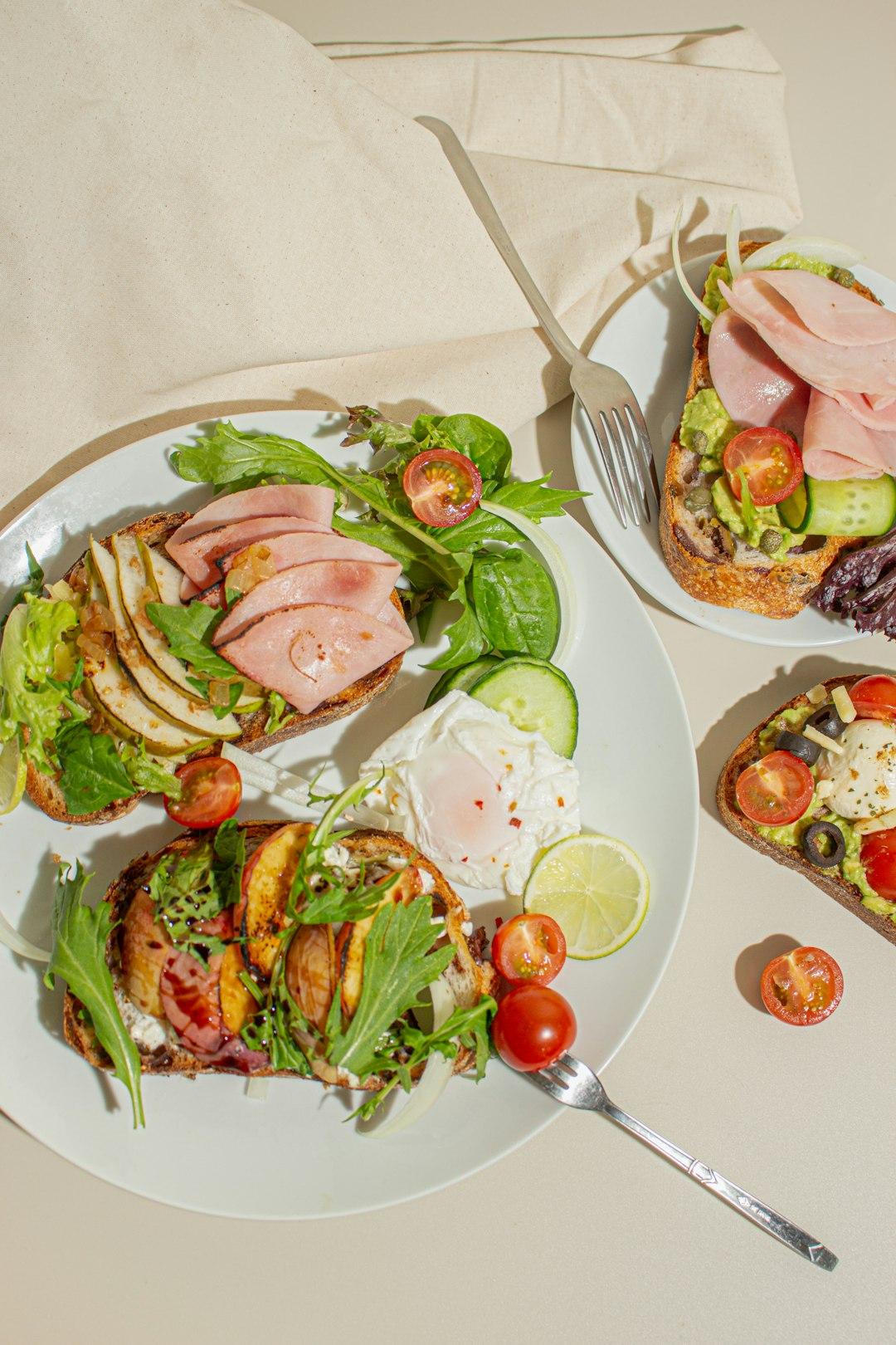 Zdrowe tosty z awokado, szynką, jajkiem i świeżymi warzywami na brunch.