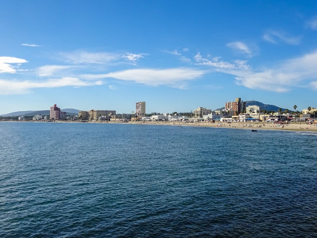 Słoneczna plaża z ludźmi, nadmorskie miasto i błękitny ocean.