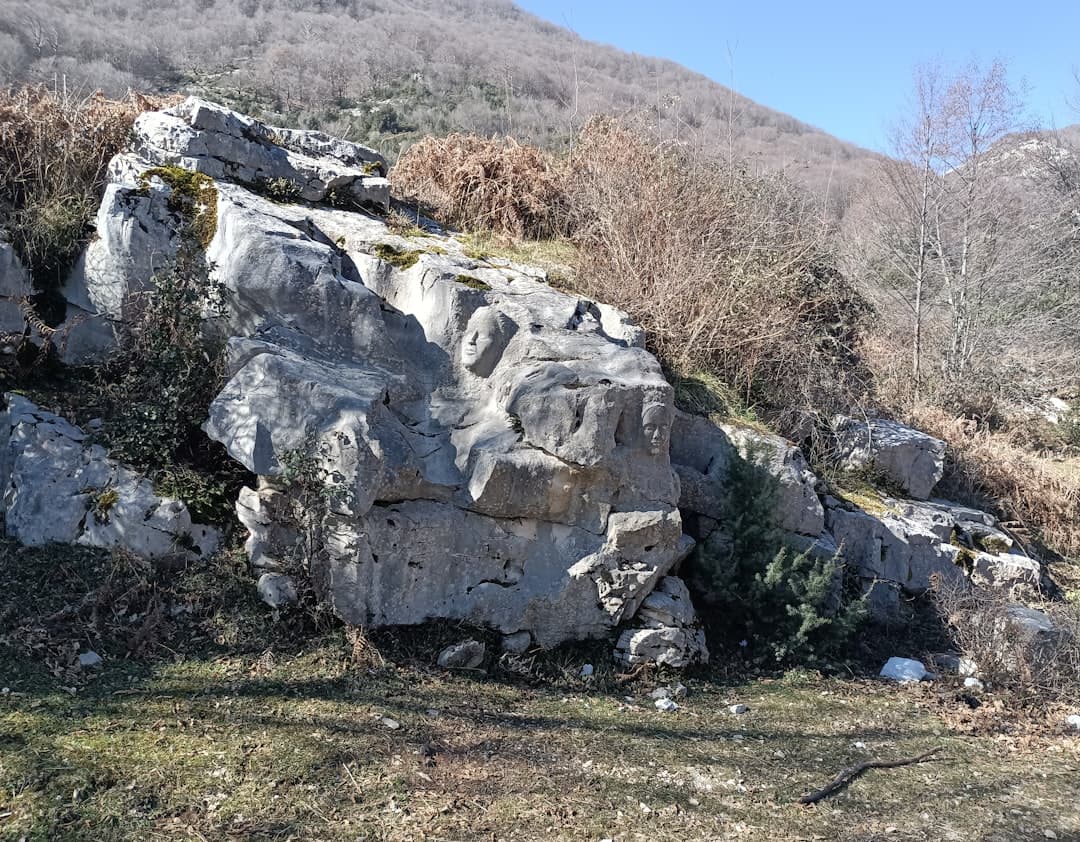 Skalne rzeźby twarzy na zboczu góry, naturalny krajobraz.