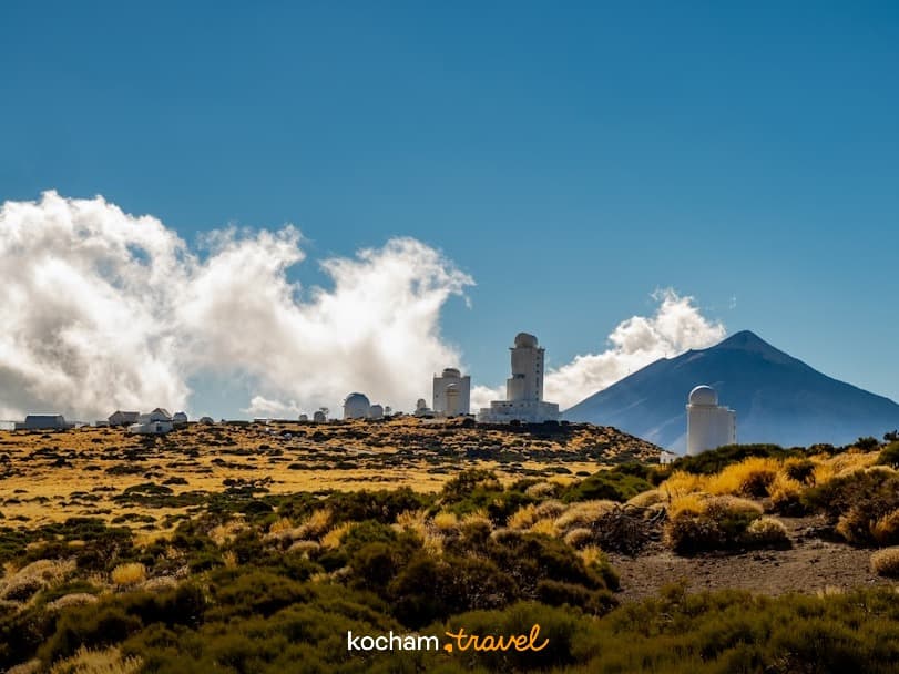 Obserwatorium astronomiczne na Teneryfie z wulkanem Teide w tle, słoneczny dzień.