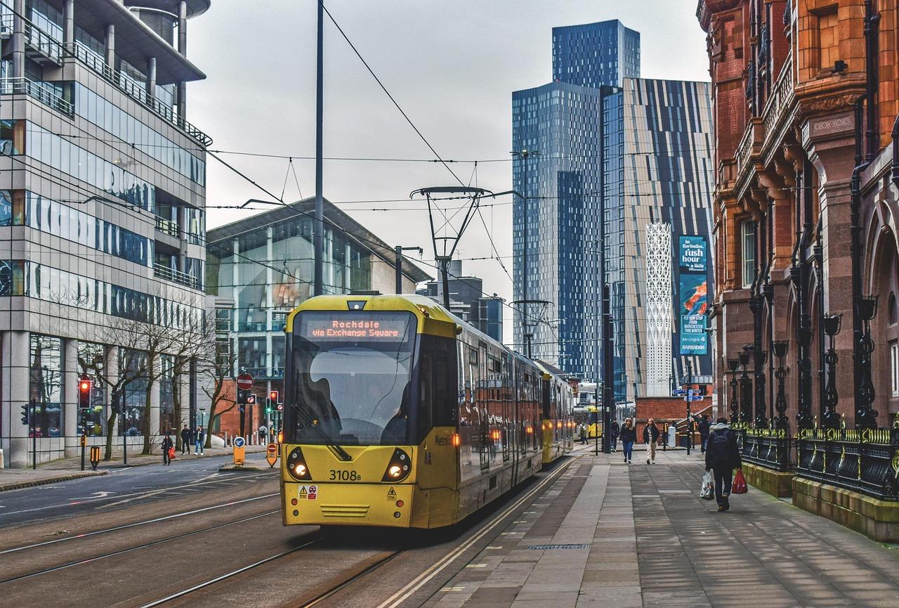 Ulica Manchesteru z żółtym tramwajem Metrolink i drapaczami chmur.