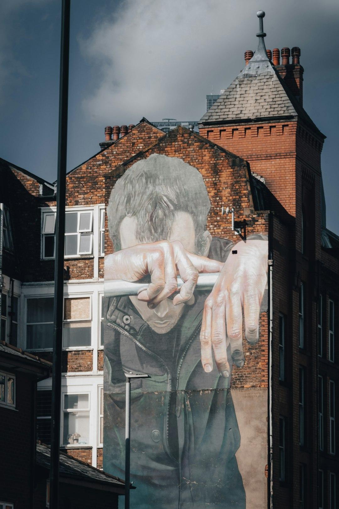Wielki mural mężczyzny na ceglanej ścianie budynku w Manchesterze.