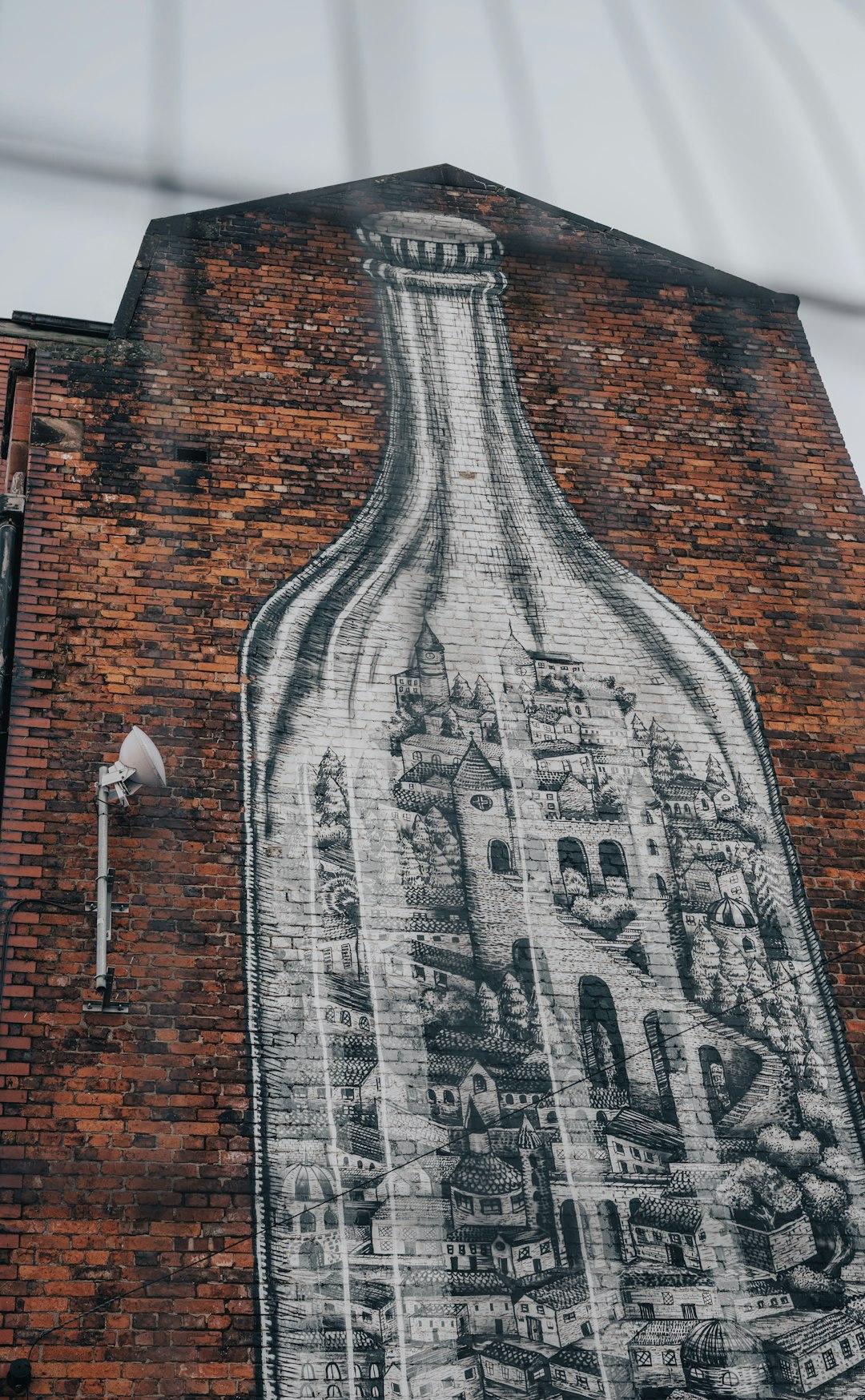 Mural przedstawiający miasto w butelce na ceglanej ścianie.