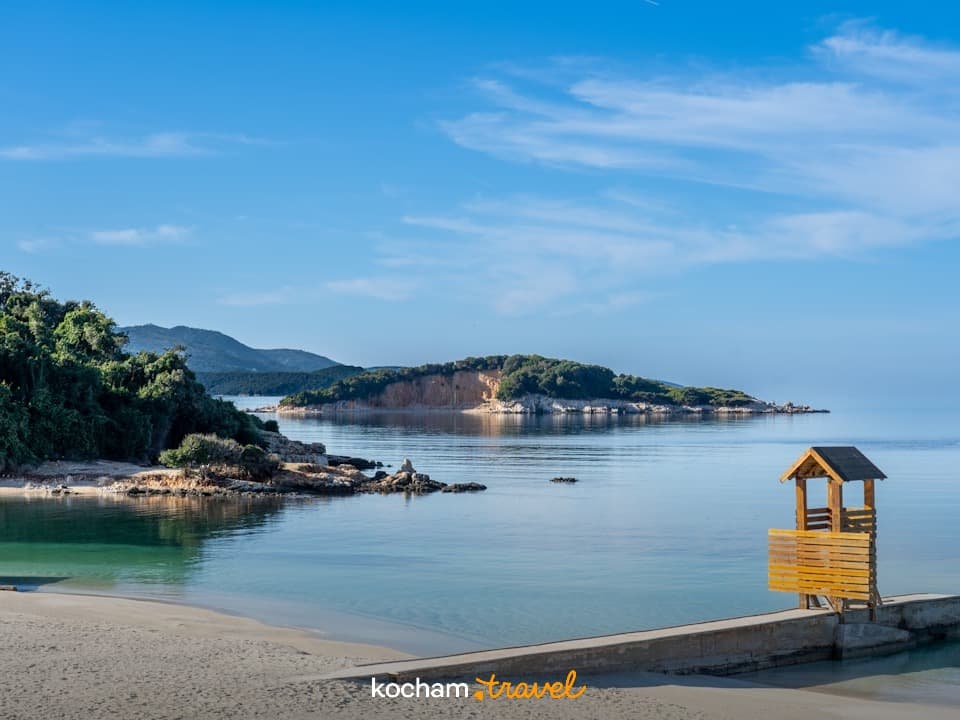 Piaszczysta plaża, turkusowe morze, zielone wyspy, drewniana budka na molo.