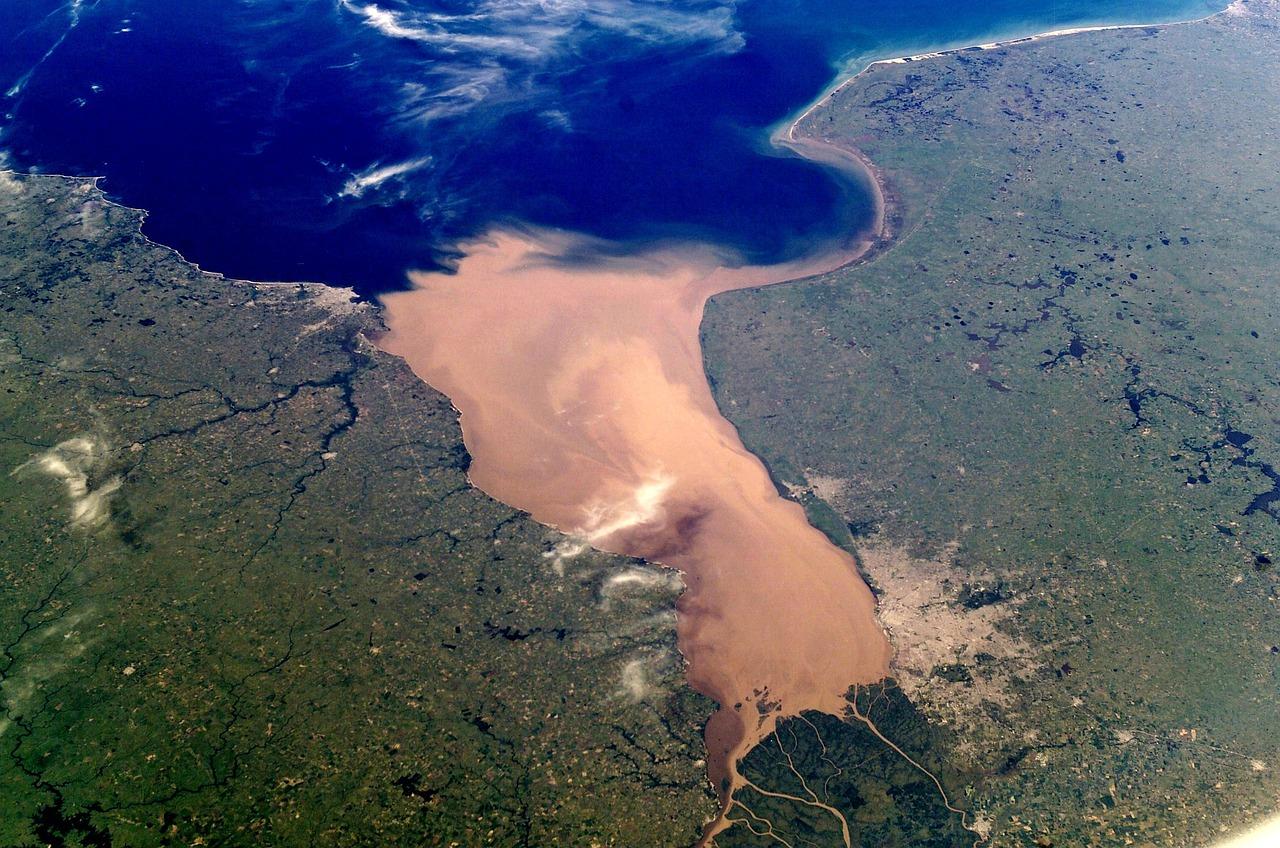 Rozległe estuarium rzeki z osadami, zielone wybrzeże, ocean.
