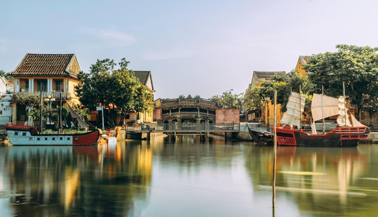 Hoi An, Wietnam: japoński most, rzeka, łodzie, zabytkowa architektura.