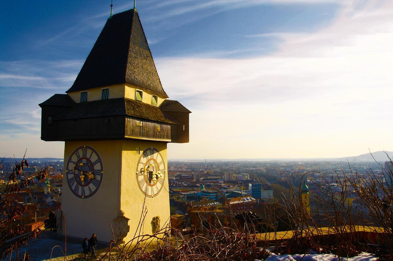Historyczna wieża zegarowa Uhrturm w Grazu z panoramą miasta.