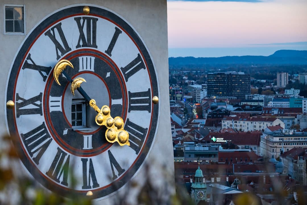 Zegar Uhrturm i panorama miasta Graz o zmierzchu.