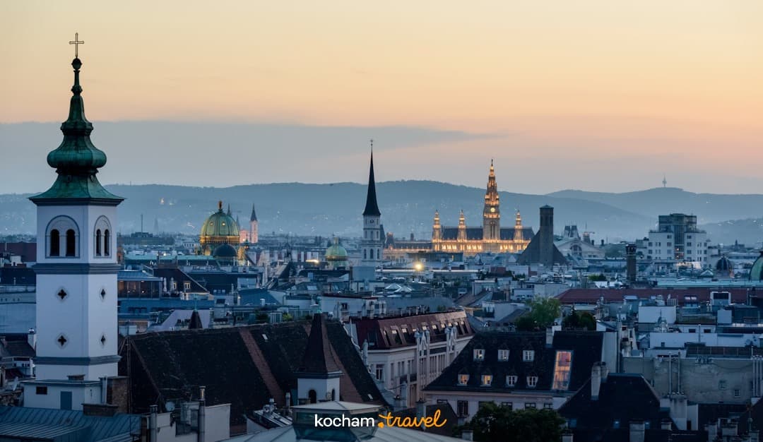 Wieczorna panorama Wiednia, oświetlony ratusz, zabytkowe kościoły, zachód słońca.