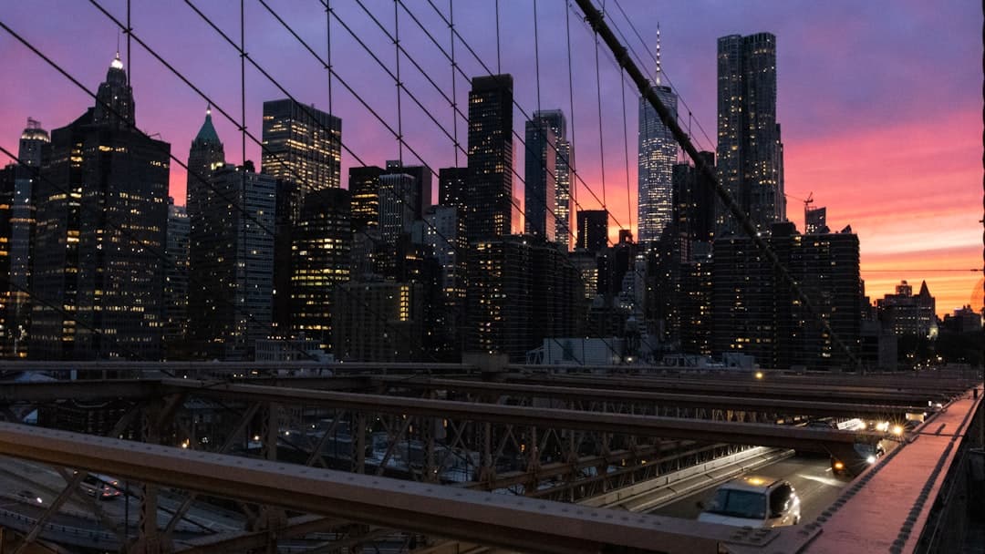 Manhattan skyline o zachodzie słońca, Most Brookliński, oświetlone wieżowce i ruch uliczny.