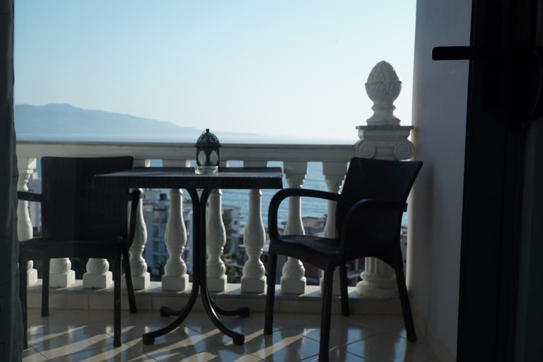Balkon z krzesłami, stolikiem i latarnią.