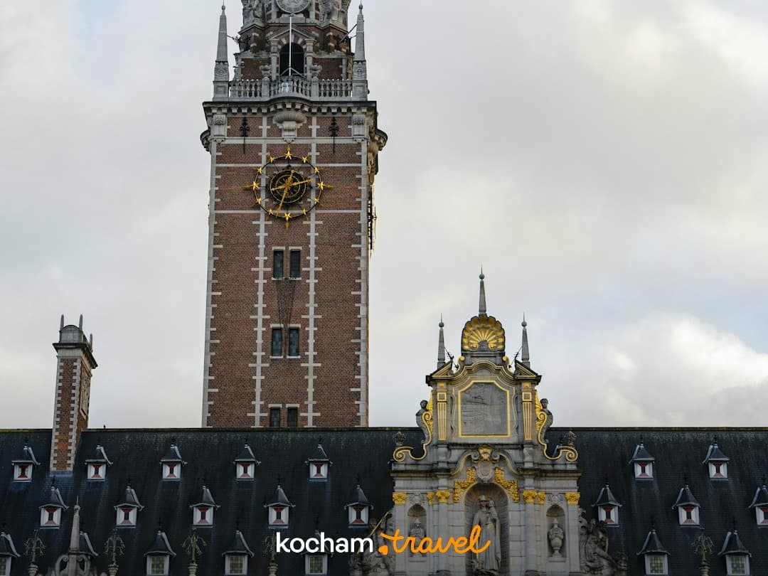 Wieża zegarowa i ozdobna fasada zabytkowego budynku uniwersyteckiego w Leuven.