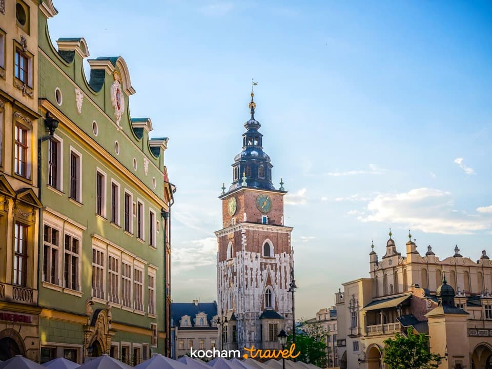 Słoneczny Rynek Główny w Krakowie z Wieżą Ratuszową i zabytkowymi kamienicami.