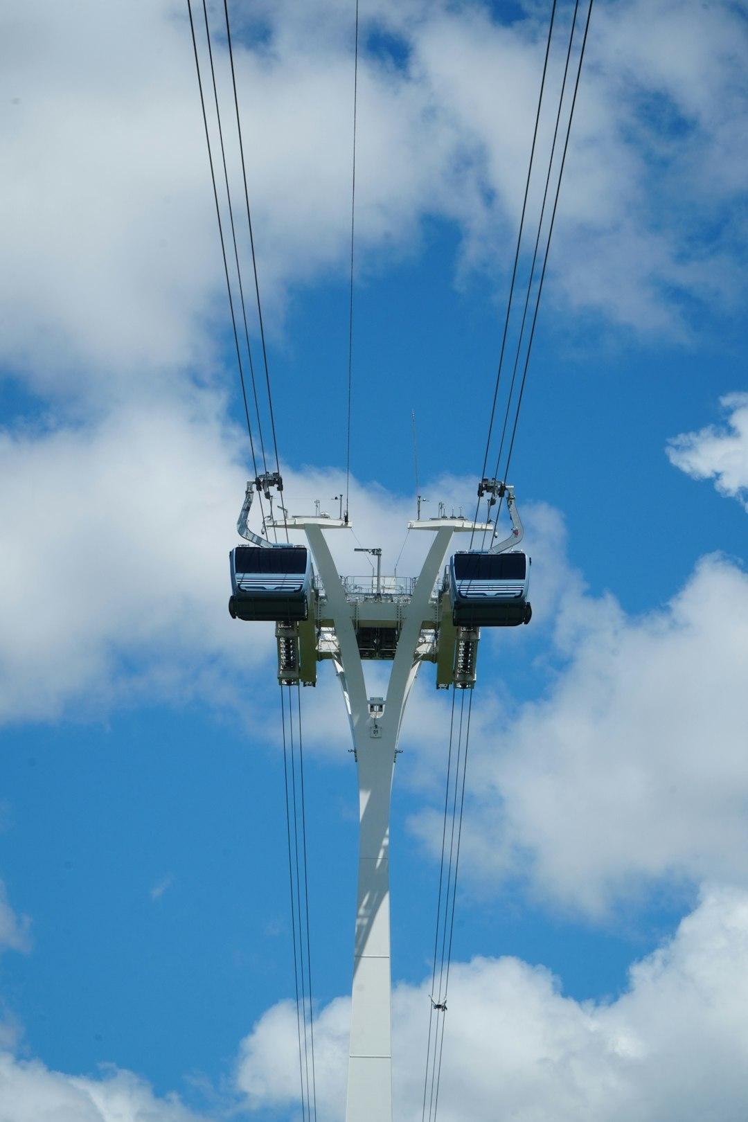 Biały pylon i dwie gondole kolejki linowej pod błękitnym niebem.