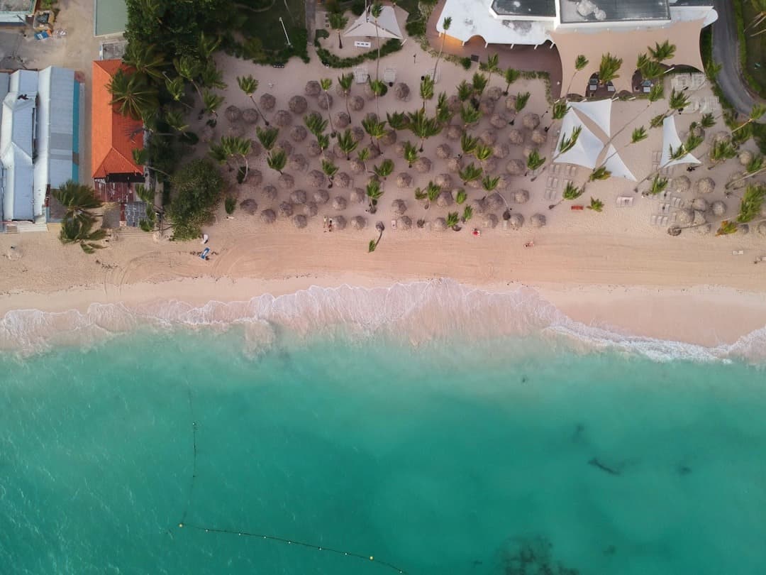 Plaża tropikalna z turkusową wodą, palmami i kurortem, widok z góry.