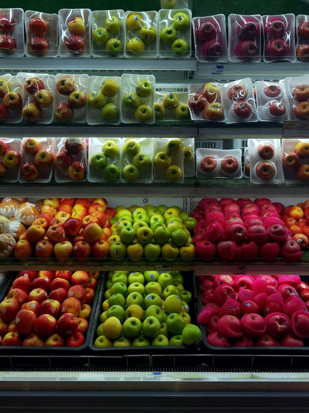 Różnorodne jabłka na półkach sklepowych w supermarkecie