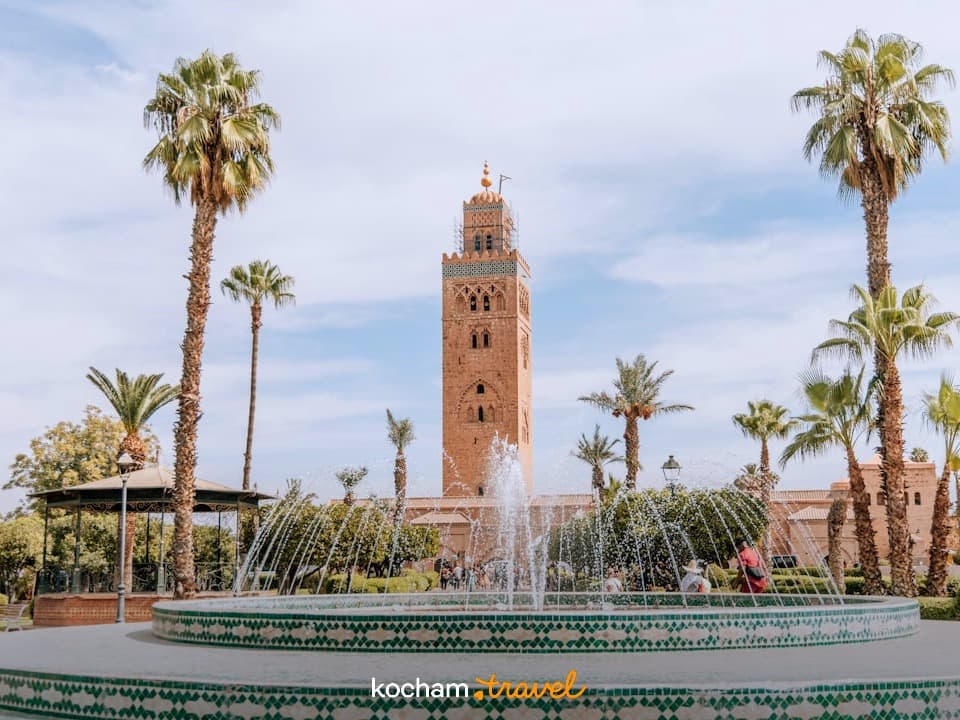 Minaret Meczetu Kutubijja, palmy i fontanna w Marrakeszu.