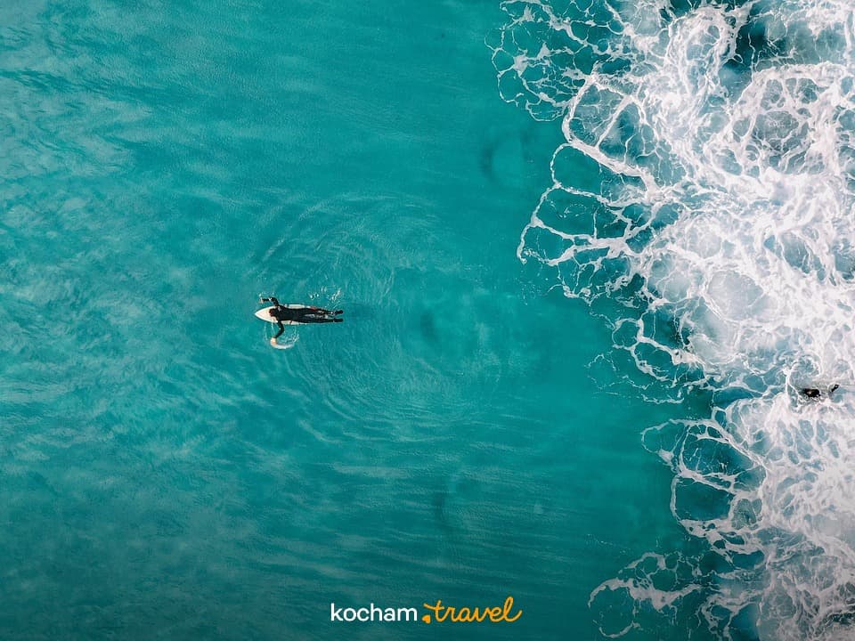Surferzy dryfujący w turkusowym oceanie z białymi falami, sporty wodne.