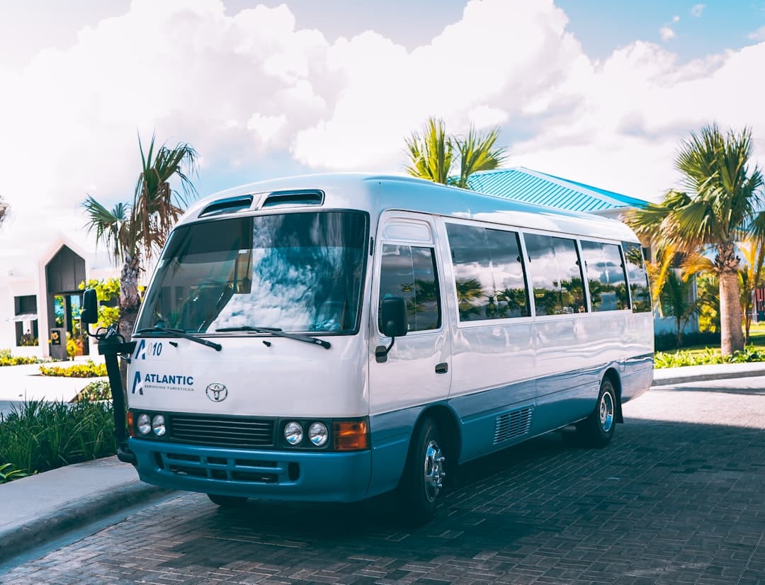 Biało-niebieski minibus turystyczny Atlantic zaparkowany pod palmami.