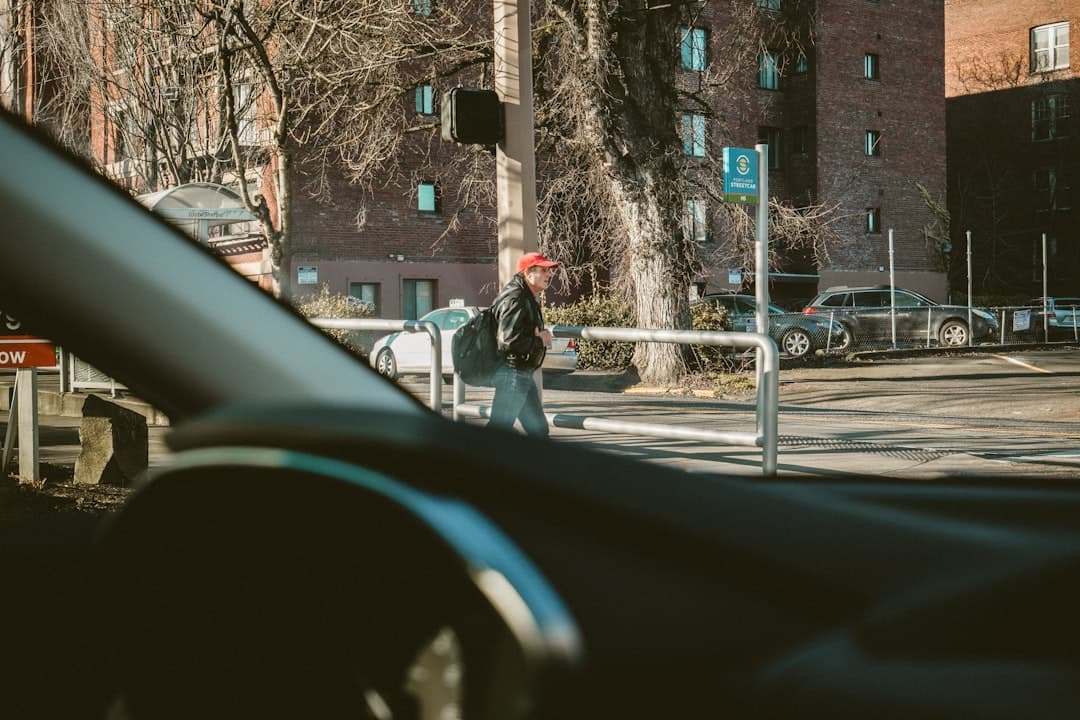 Mężczyzna w czerwonej czapce przechodzący przez ulicę w słoneczny dzień.