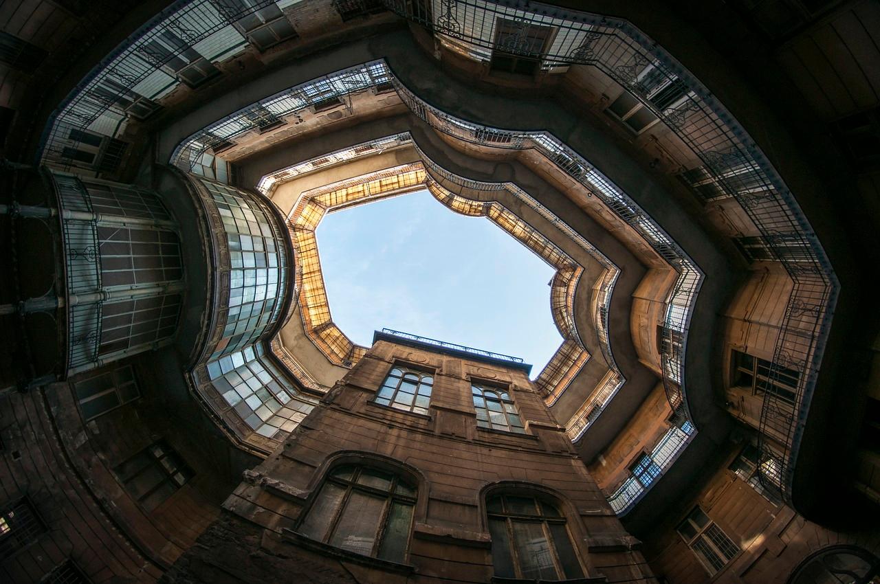 Architektura starego dziedzińca z balkonami i niebem, widok z dołu.