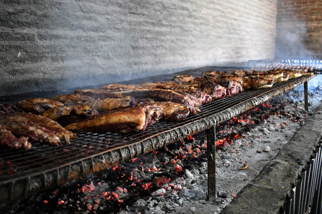 Duże kawałki mięsa grillowane na ruszcie nad żarem węglowym.