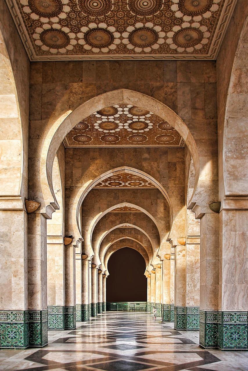 Zdobiony korytarz z łukami, architektura islamska, mocne cienie.
