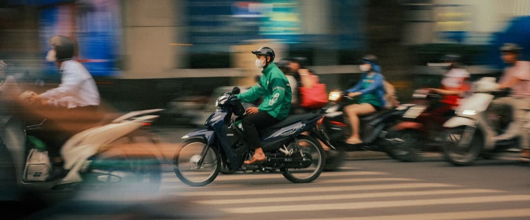 Ruchliwa ulica azjatyckiego miasta, motocykliści i dostawca w maskach.