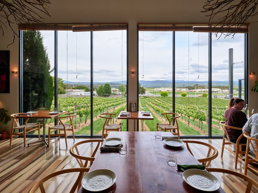 Wnętrze restauracji z panoramicznym widokiem na zieloną winnicę.