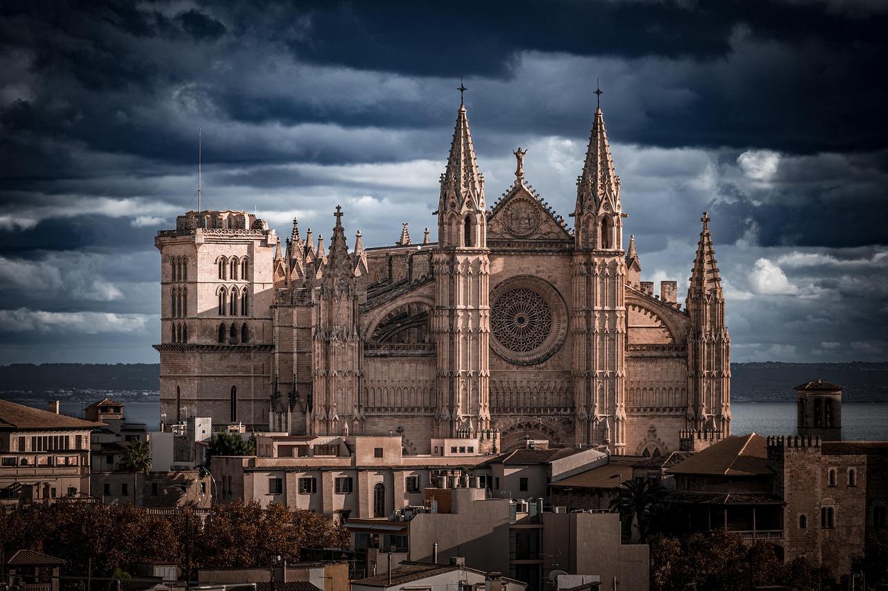 Gotycka katedra La Seu w Palmie pod dramatycznym, burzowym niebem.
