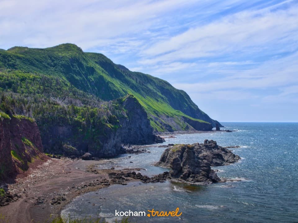 Skaliste wybrzeże, zielone wzgórza, błękitny ocean, naturalny krajobraz.