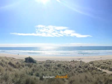 Panoramiczny widok na słoneczną plażę z wydmami i oceanem.