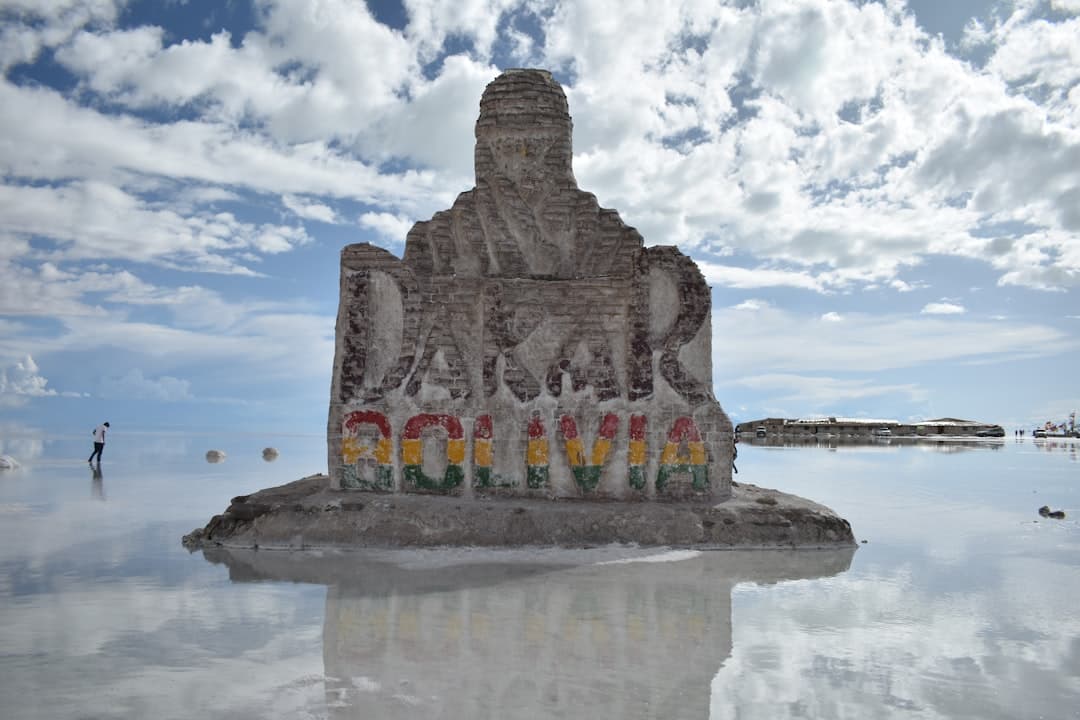 Monument Dakar Boliwia na Salar de Uyuni, odbijający się w tafli wody.