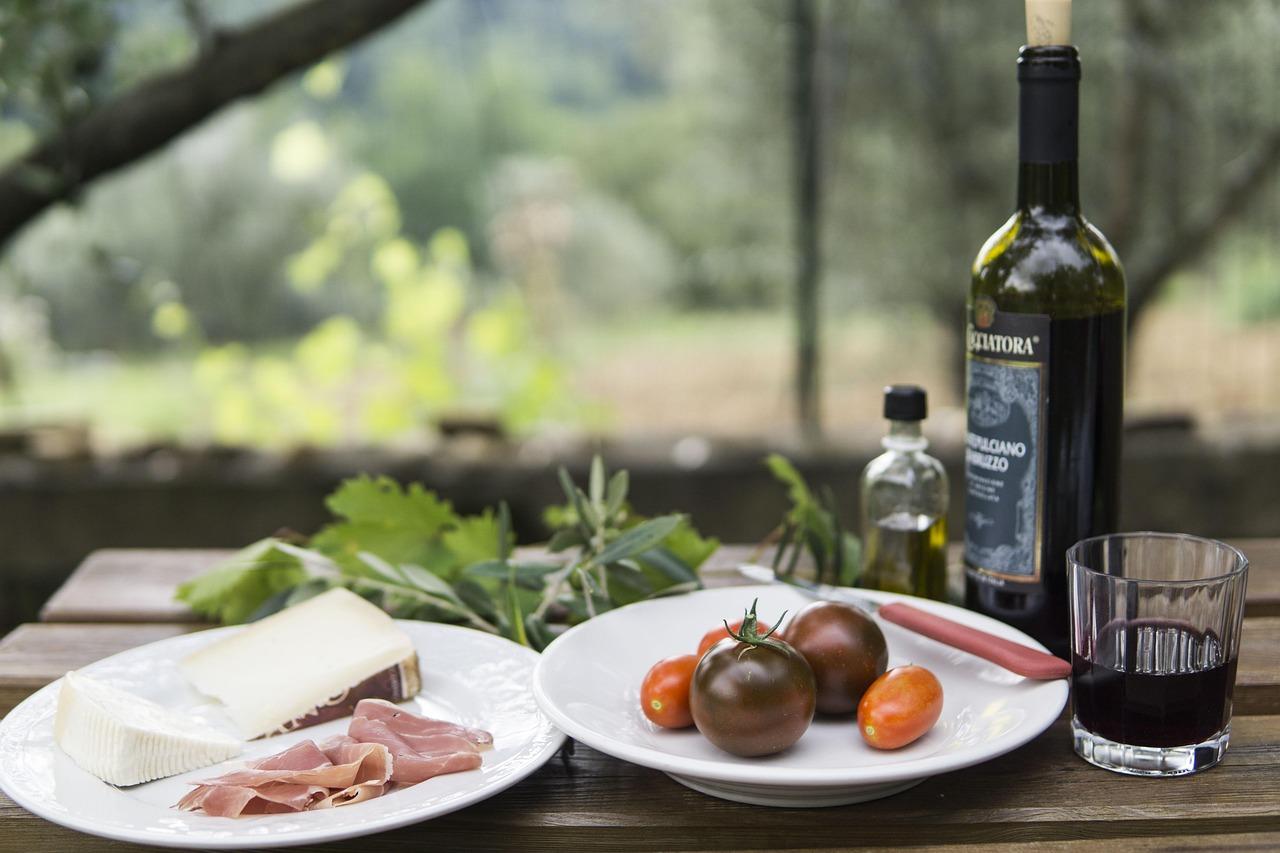 Włoski piknik: ser, prosciutto, pomidory, czerwone wino, oliwa.