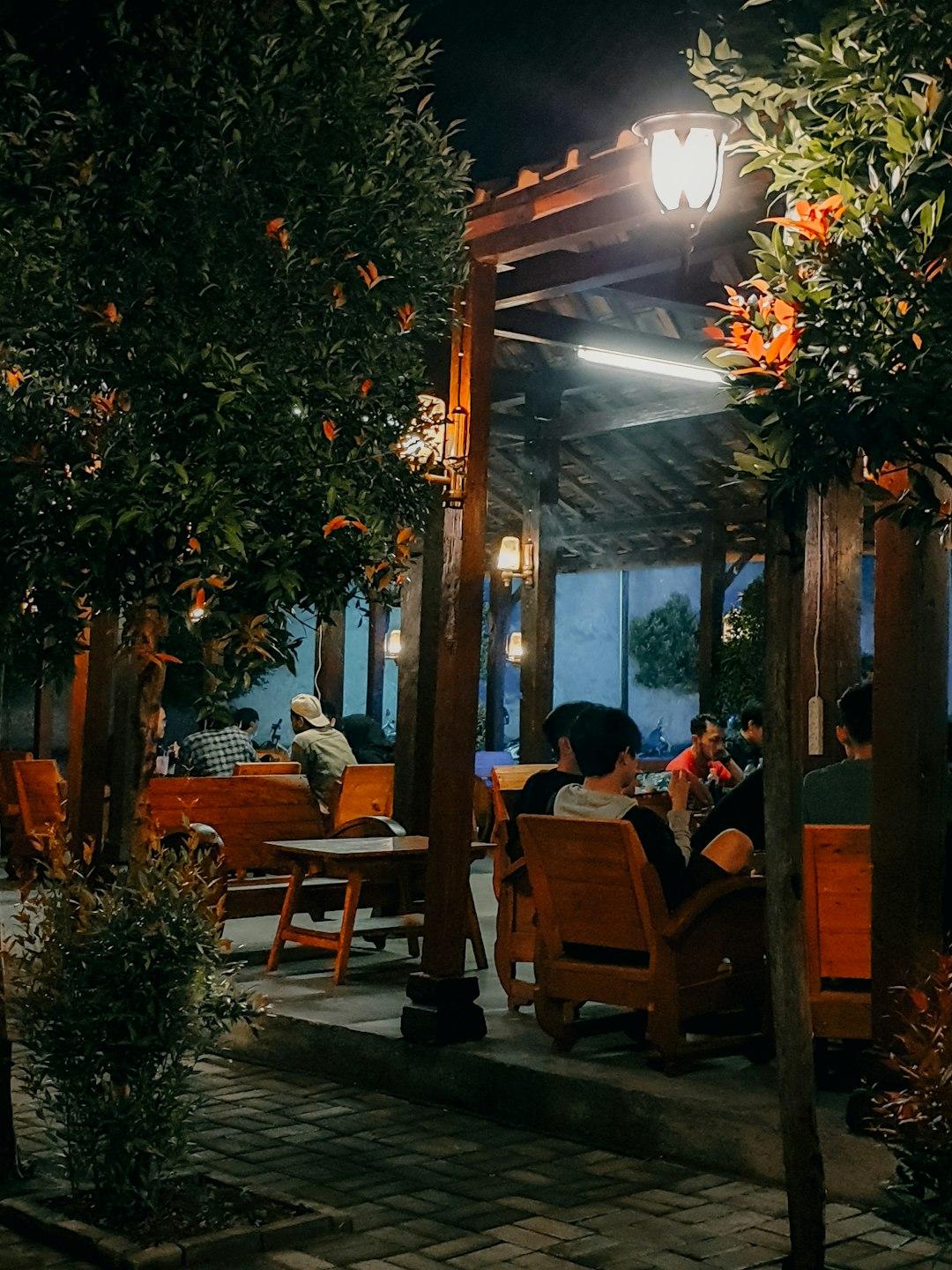 Wieczór w przytulnej restauracji ogrodowej z drewnianymi meblami i roślinami.