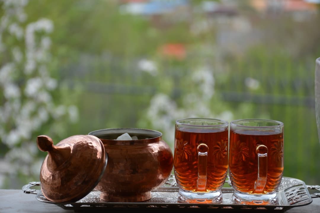 Dwie szklanki herbaty i miedziana cukiernica na ozdobnej tacy.