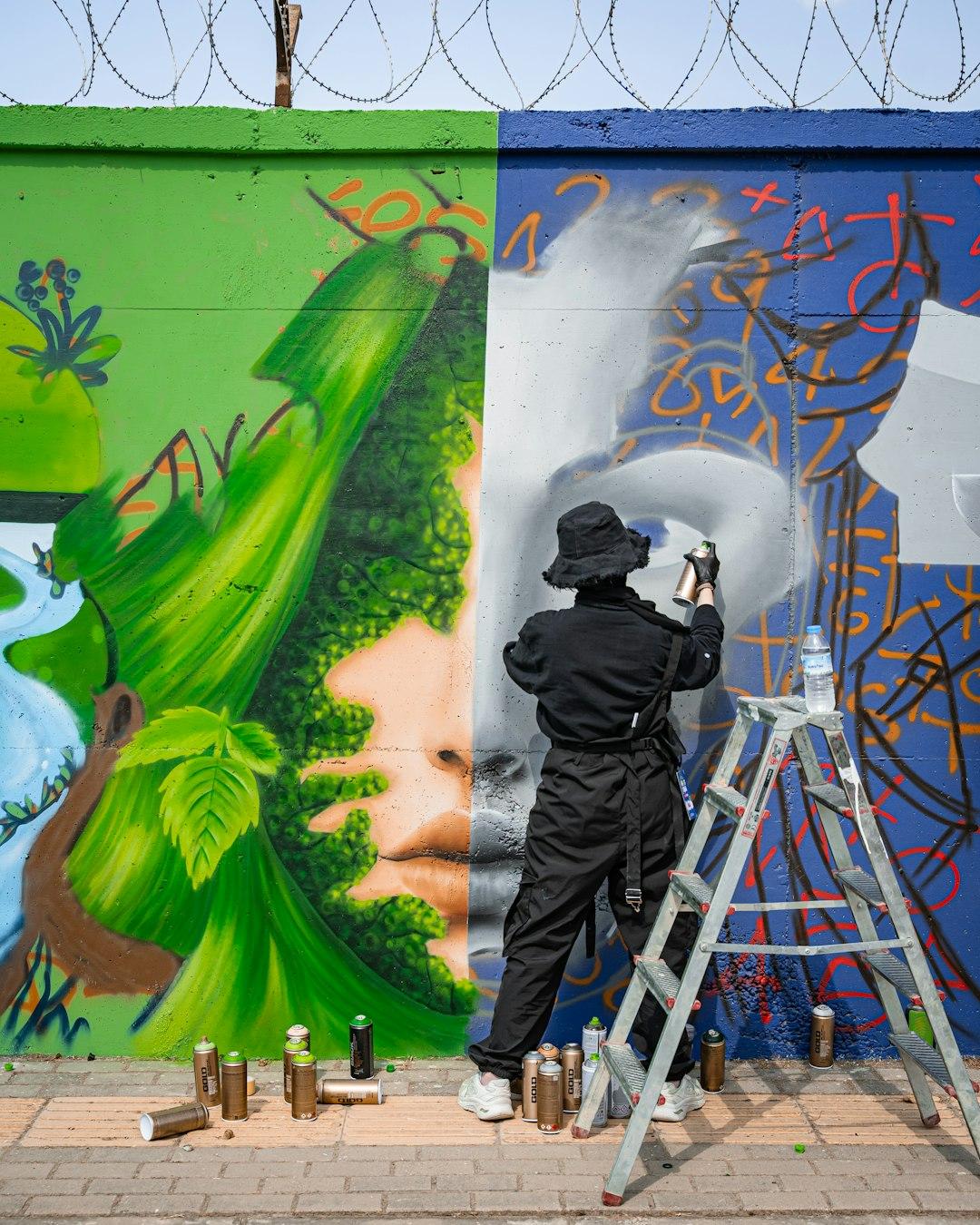 Artysta maluje barwny mural ścienny z naturą i abstrakcją.