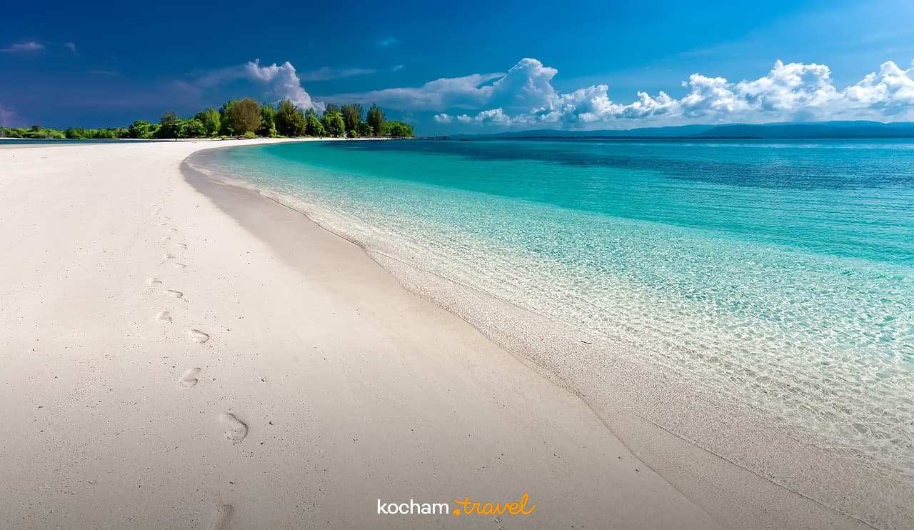 Biała piaszczysta plaża, krystalicznie czysta turkusowa woda, tropikalna wyspa.