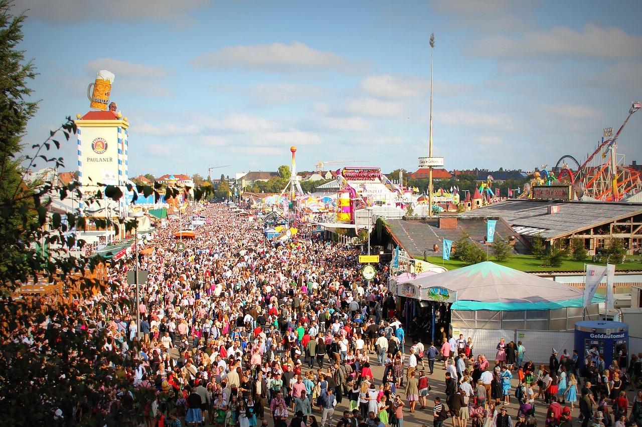 Tłumy ludzi bawiących się na Oktoberfest, namioty piwne Paulaner, karuzele.