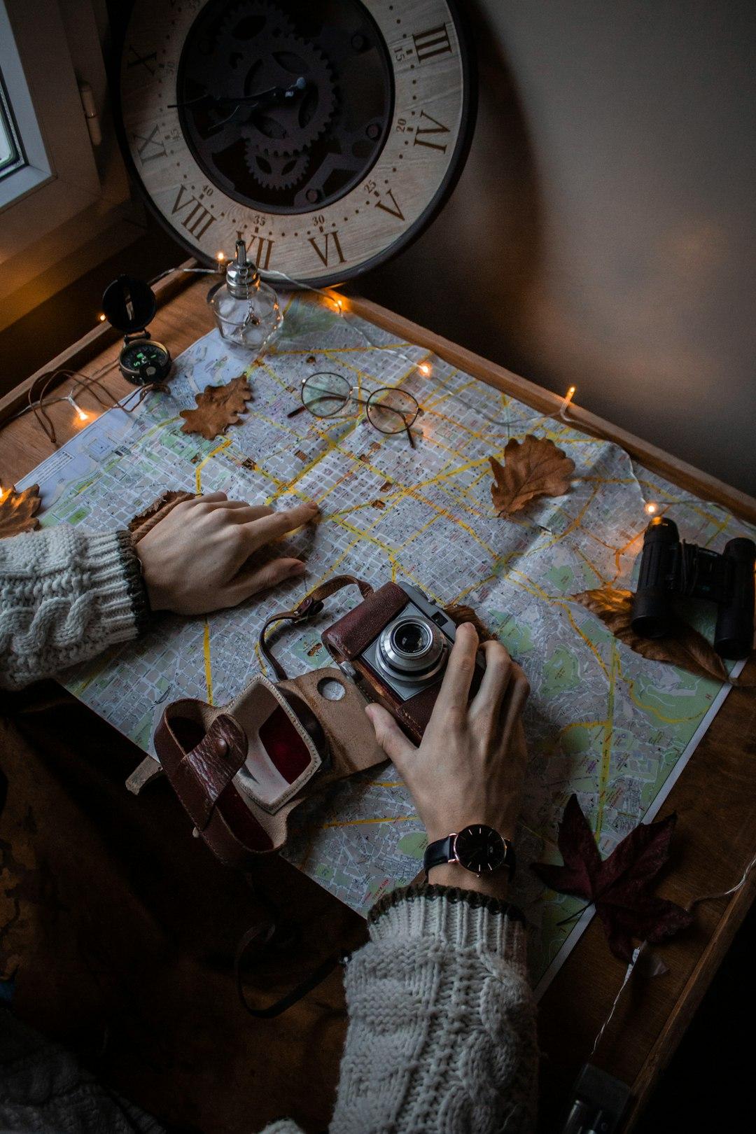 Mapa, aparat vintage, kompas i ręce planujące jesienną podróż.
