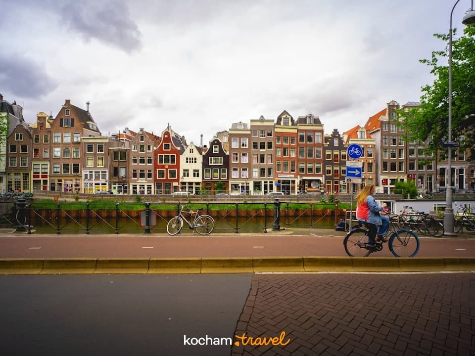 Tradycyjne kamienice nad kanałem w Amsterdamie, rowerzysta na ulicy
