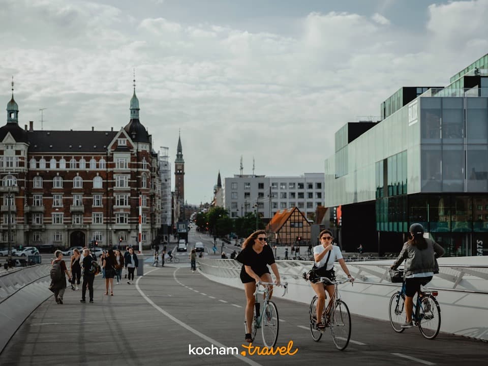 Rowerzyści i piesi na moście w Kopenhadze, nowoczesna i historyczna architektura miasta.