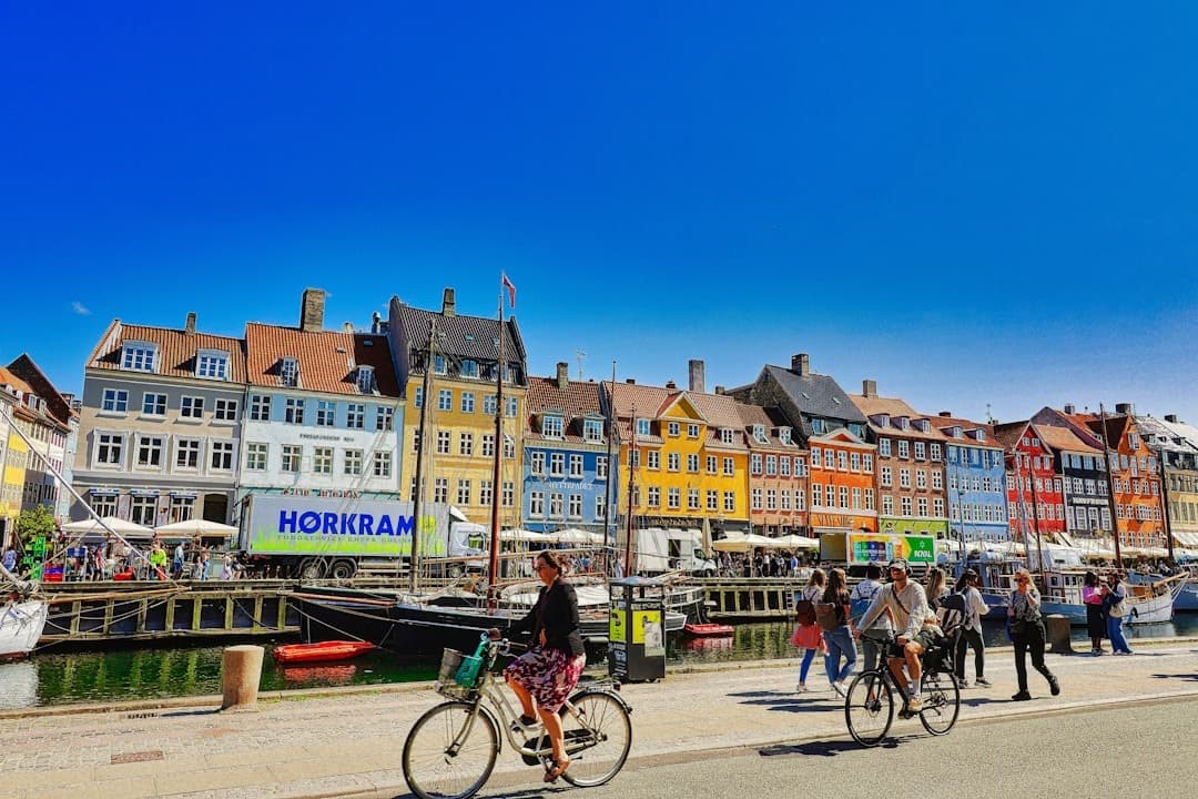 Kopenhaga Nyhavn, kolorowe kamienice, kanał, rowery, ludzie w słońcu.